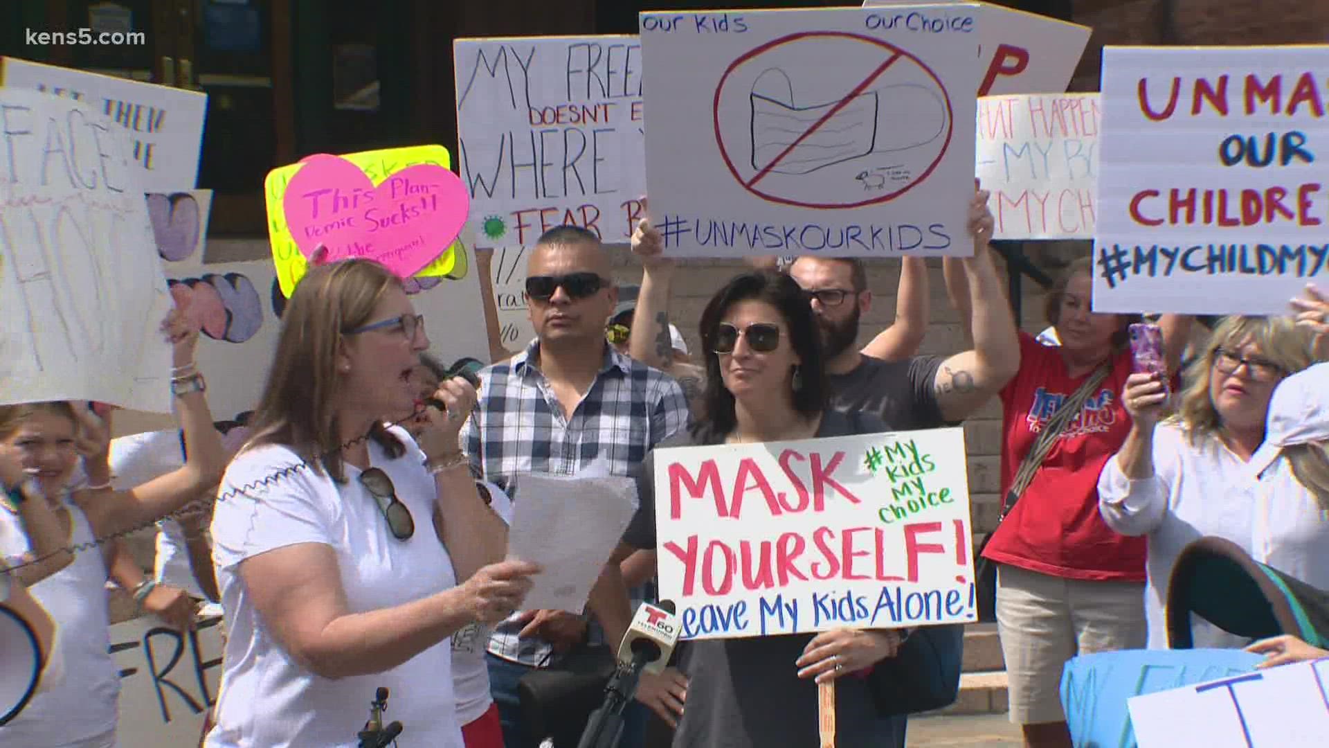 Nearly 100 protesters gathered with signs reading sentiments like "Masks are my choice" and "Unmask our children." Doctors, meanwhile, say pediatric cases are up.