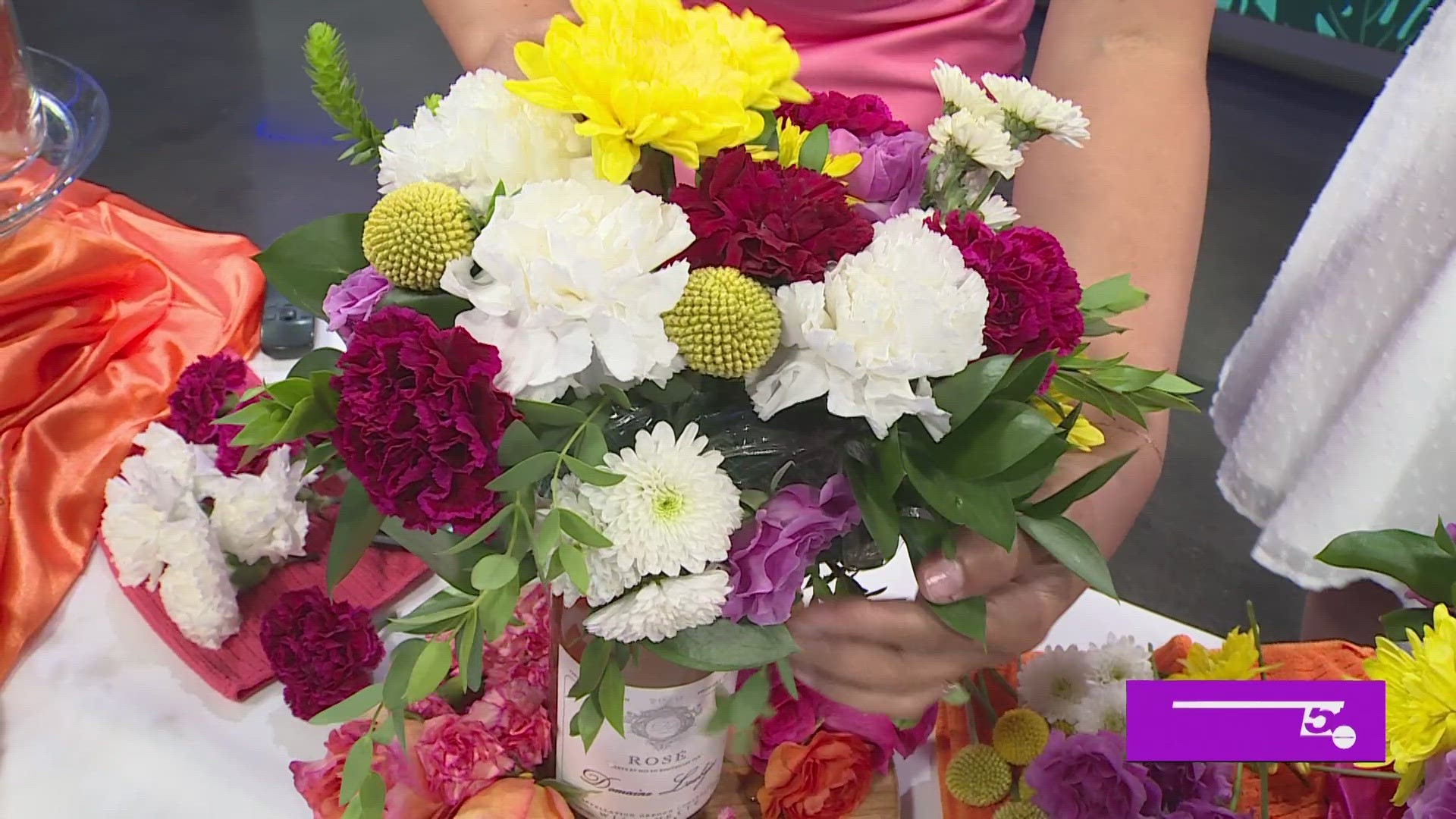 Kailey Loza with Blooms in Grace shows Clarke how to make a flesh flower crown for a wine bottle, perfect for summer decor.